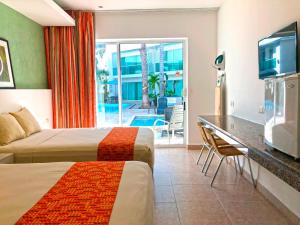 a hotel room with two beds and a television at Hotel Los Cocos Chetumal in Chetumal