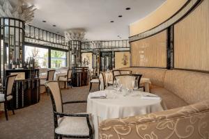 una sala da pranzo con tavoli e sedie bianchi di Hotel Imperiale Rimini & SPA a Rimini