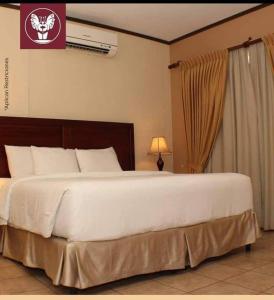 a large white bed in a bedroom with a lamp at HOTEL PRIMAVERA BOUTIQUE in San Pedro Sula