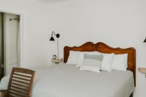 a bed with a wooden headboard and white pillows at Blue Moon Motel in Lake George