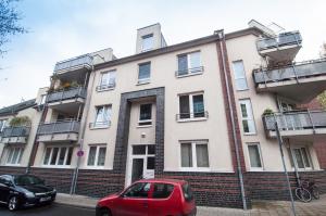 ein rotes Auto, das vor einem Gebäude parkt in der Unterkunft Ferienwohnung Neuss in Neuss