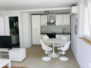 a white kitchen with a table and white chairs at Mon littoral ( rez-de-jardin ) 100 m de la plage in Le Pradet