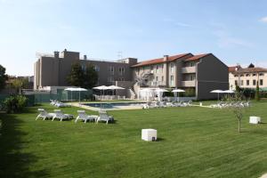 a lawn with chairs and a pool and buildings at Hotel Franz in Gradisca dʼIsonzo