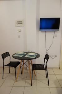 d'une table, de deux chaises et d'une télévision dans la chambre. dans l'établissement Kiki's cosy apartments, à Néa Khilí