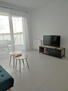ein Wohnzimmer mit einem TV, 2 Tischen und einem Sofa in der Unterkunft T2 avec balcon tout équipé 300m marché central in Royan
