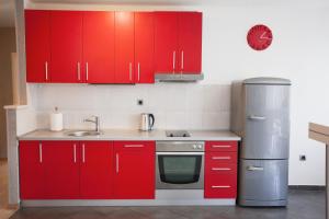 cocina con armarios rojos y nevera de acero inoxidable en Apartment Red, en Belgrado