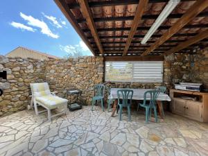 d'une terrasse avec une table et des chaises ainsi qu'un mur en pierre. dans l'établissement Le Fenouillet Cottage proche des Grands Buffets, à Narbonne