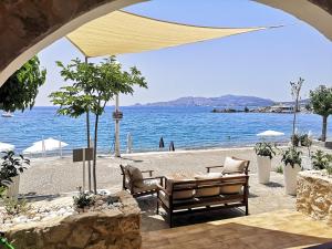 a view of a beach with two benches and the water at Relax Seaside House by living in blue in Haraki