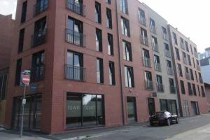 a red brick building with a car parked in front of it at Modern 1 Bedroom Apartment by BOLD Apartments in Liverpool