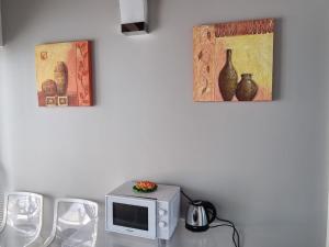 a table with a microwave and two pictures on the wall at Villa Glamour in Taormina