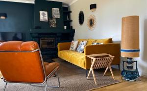 - un salon avec un canapé jaune et une cheminée dans l'établissement Maison sur le golfe du Morbihan vue mer, à Plougoumelen