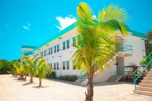 a white building with palm trees in front of it at Best Western Grand Baymen Gardens in San Pedro