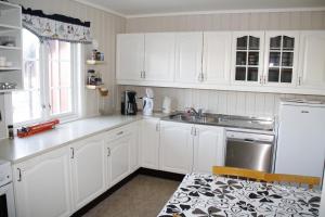 una cocina blanca con armarios blancos y fregadero en Flekkerøy 20 persons en Kristiansand