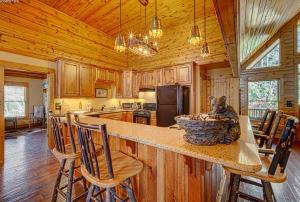 a kitchen with a counter and chairs in a cabin at Cozy Creekfront Family Cabin-Pet Friendly -GameRm-Hot Tub in Hiawassee