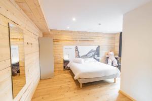 Schlafzimmer mit einem weißen Bett und Holzwänden in der Unterkunft Esplanade Hotel in Diekirch