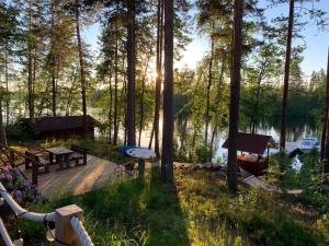a wooden deck with benches and a boat on a lake at Villa Taikuri in Kyläniemi