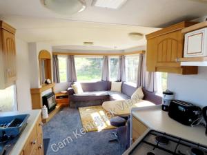 a living room with a couch and a kitchen at Carn Kenidjack View Caravan, space, peace and tranquillity in Penzance