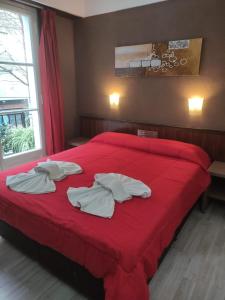 a bedroom with a red bed with towels on it at Hotel Flamingo in Mar del Plata