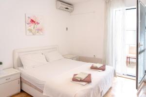 a white bedroom with a bed with towels on it at Guest House Jasna in Budva