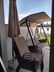 two chairs and an umbrella on a balcony at Tandem apartman in Kápolnásnyék