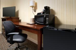 a room with a desk with a microwave and a television at American Inn of Bethesda in Bethesda