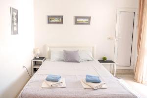 a white bedroom with a large white bed with blue pillows at Guest House Jasna in Budva