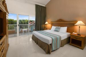 Habitación de hotel con cama y balcón en Hodelpa Garden Suites - All Inclusive, en Juan Dolio