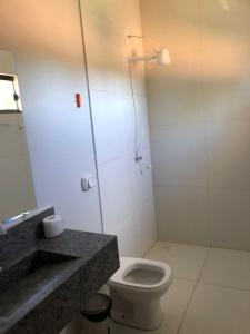 a bathroom with a toilet and a sink and a mirror at Pousada Amanhecer no Jalapão in São Félix do Tocantins