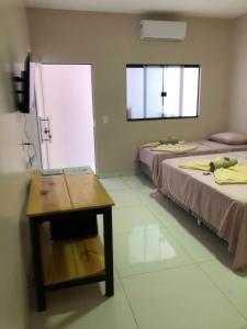 a room with two beds and a table and a window at Pousada Amanhecer no Jalapão in São Félix do Tocantins