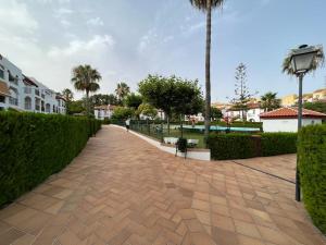 a brick walkway in a park with palm trees and buildings at Precioso apartamento con ubicación perfecta en playa Islantilla in Islantilla