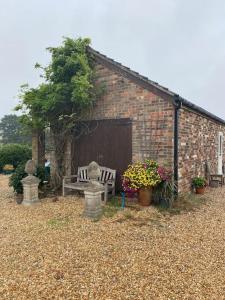 a brick building with a bench and flowers in a yard at Beautiful Rural Self Contained Farm Annex in Hordle