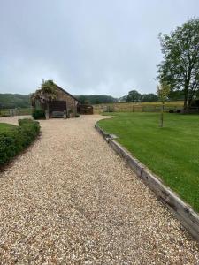 eine Kieseinfahrt mit einem Haus und einem Grasfeld in der Unterkunft Beautiful Rural Self Contained Farm Annex in Hordle