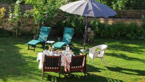 una mesa y sillas con una sombrilla en un patio en Les Papouz, en Gommécourt