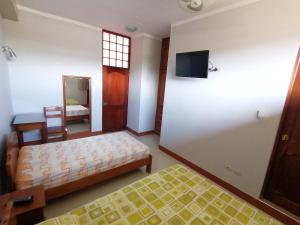 a bedroom with a bed and a tv on a wall at Rosa Victoria in Tarapoto