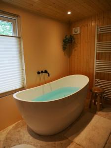 a large white tub in a bathroom with a window at The Sunbird Inn - with luxurious bathroom in Diessen