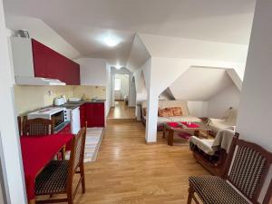a kitchen and living room with red cabinets and a table at Apartmani Djokić sa bazenom in Soko Banja