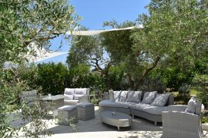 a patio with a couch and chairs and trees at B&B Li Ccoti in Cannole