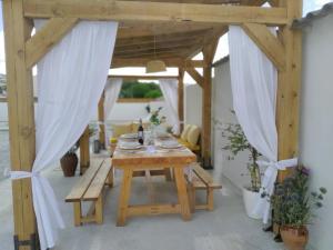 a wooden table in a pavilion with white curtains at Atalaya de los Bermejales Villa privada piscina in Los Morales