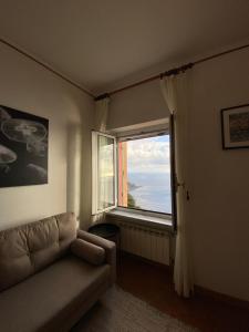 uma sala de estar com um sofá e uma grande janela em Appartamento Victoria em Camogli