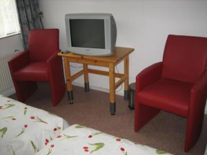 a room with two red chairs and a tv on a table at B&B Ans en Ben Streppel in Twello