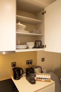 a kitchen with white cabinets and dishes on shelves at Atrium Areias in Viana do Castelo