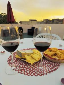 dois copos de vinho tinto e queijo numa mesa em Rosa's Apartment with Terrace em Cagliari