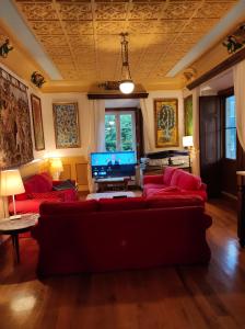 a living room with red couches and a flat screen tv at CASA DE INDIANoS, UNA EXPERIENCIA UNICA EN EL CENTRO DE CANTABRIA in San Vicente de Toranzo