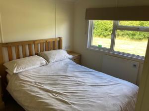 a bed in a bedroom with a window at Lakeside cabin set in the Kentish countryside in Bethersden
