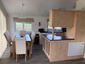 a kitchen and dining room with a table and chairs at Lakeside cabin set in the Kentish countryside in Bethersden
