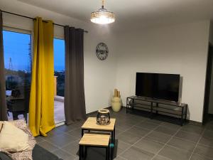 a living room with a flat screen tv and yellow curtains at Résidence Pasturella in Bastia