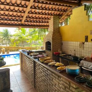 an outdoor kitchen with food on a counter next to a pool at Rancho Colcha de Retalho in Caucaia