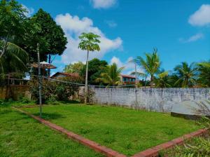 a garden with a fence and trees and a wall at Rancho Colcha de Retalho in Caucaia