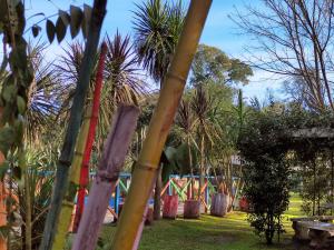 un jardín con un parque infantil con palmeras y una valla en Studios La Bella Vida en Escobar en Belén de Escobar