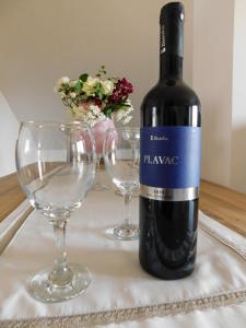 a bottle of wine sitting next to two wine glasses at Apartman Lara in Otočac